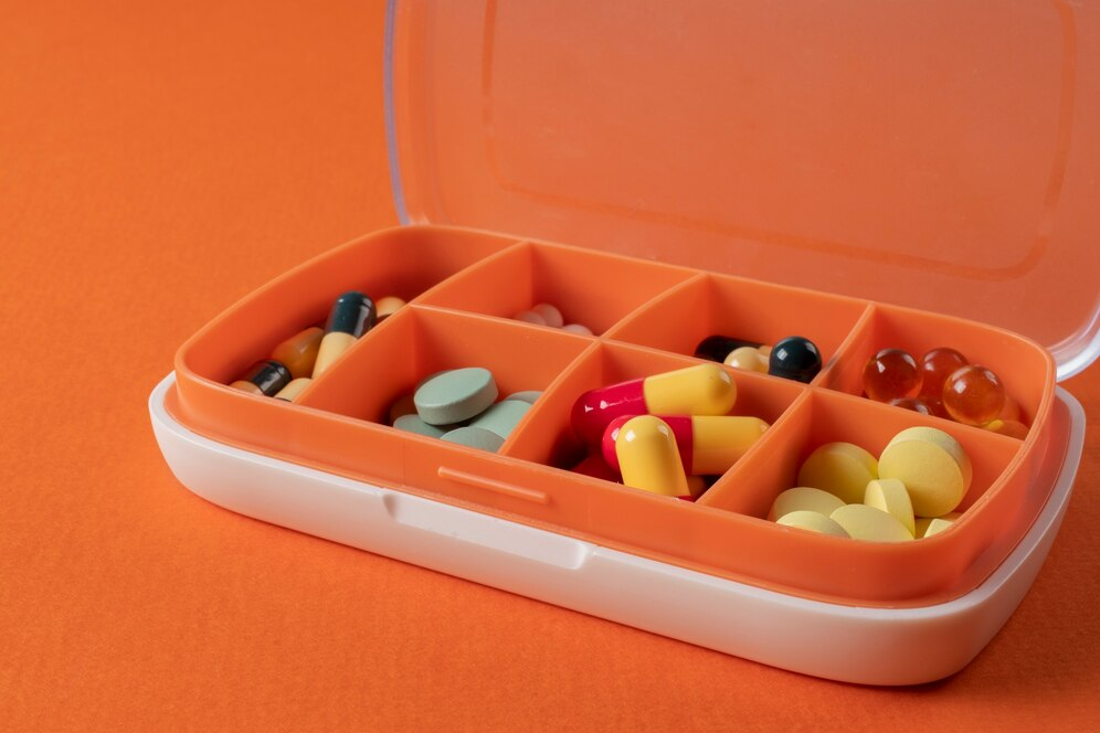 изображение на оранжевом фоне в центре находится таблетница с витаминами группы В